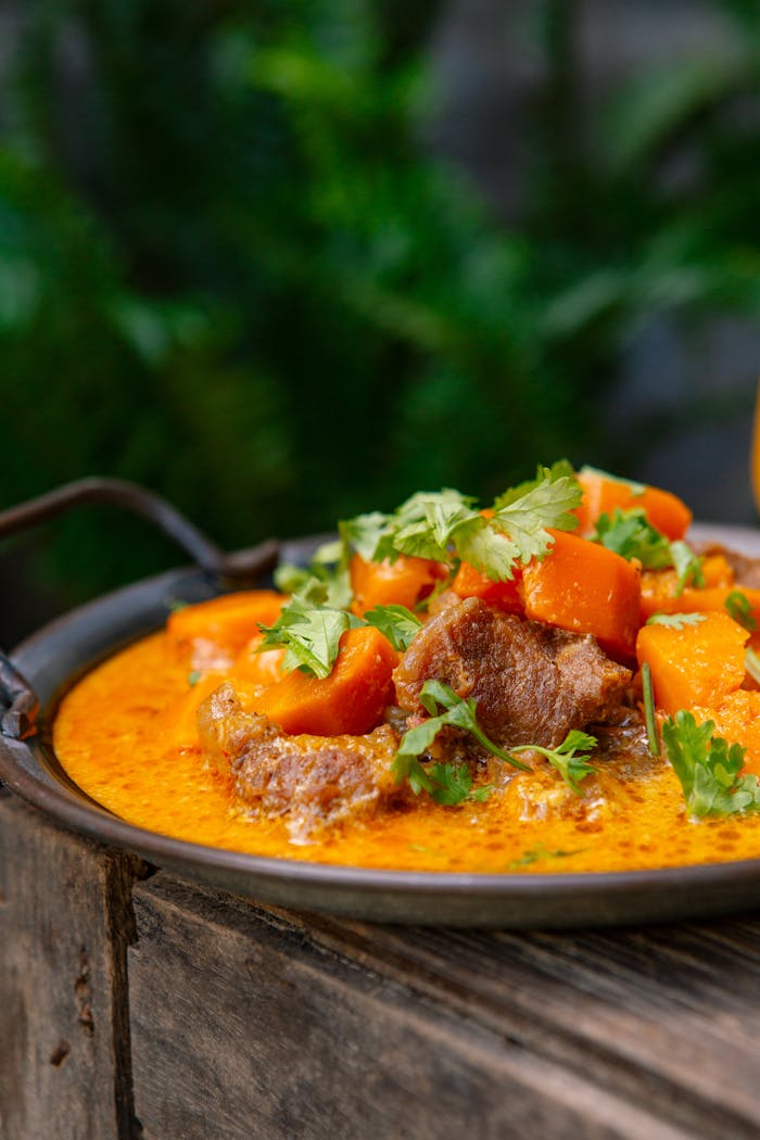 Close-up of Vietnamese beef curry with fresh herbs and vegetables outdoors.